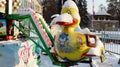 The empty carousel is covered with snow. Close up of snow covered colorful ducks carousel at fun fair carnival during winter