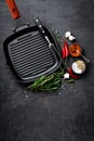 Empty cast-iron grill pan with ingredients for cooking on black background Royalty Free Stock Photo