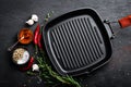 Empty cast-iron grill pan with ingredients for cooking on black background Royalty Free Stock Photo