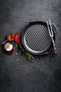 Empty cast-iron grill pan with ingredients for cooking on black background Royalty Free Stock Photo