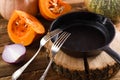 Empty cast iron pan with two forks on wood slab decorated with r