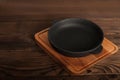 Empty cast iron round frying pan on textured wooden background close-up and copy space Royalty Free Stock Photo