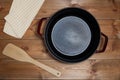 Empty cast iron sause pan with nepkin and spatula on wooden table background, top view Royalty Free Stock Photo