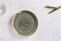 Empty ceramic green plate, a glass of water and rosemary branches on a gray background. Top view Royalty Free Stock Photo