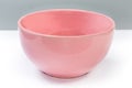 Empty ceramic pink bowl on a white surface, side view