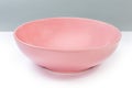 Empty ceramic pink plate on a white surface, side view