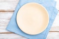 Empty ceramic plate on white wooden background and blue linen textile. Top view, close up Royalty Free Stock Photo