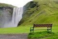 An empty chair facing Skogafoss waterfall