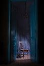 Empty chair in light behind blue massive vintage doors indoor.