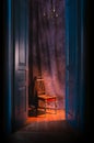 Empty chair in light behind blue massive vintage doors indoor.