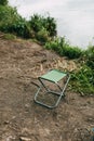 An empty chair for relaxing or fishing stands on the bank of a river or lake