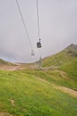 Empty chairlift in ski resort. Shot in summer with green grass and no snow. Cloudy weather. Royalty Free Stock Photo