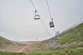 Empty chairlift in ski resort. Shot in summer with green grass and no snow. Cloudy weather. Royalty Free Stock Photo