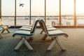 Empty chairs in the departure hall at airport with airplane taking off at sunset. Travel and transportation in airport concepts. Royalty Free Stock Photo