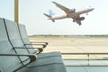 Empty chairs in the departure hall at airport on background of airplane taking off. Travel concept Royalty Free Stock Photo