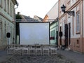 Empty chairs and projection screen outdoors on the street, open air cinema Royalty Free Stock Photo