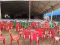 Empty chairs of red green and brown color lying in the tent disorganised.