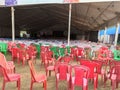 Empty chairs of red green and brown color lying in the tent disorganised.