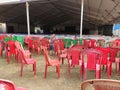 Empty chairs of red green and brown color lying in the tent disorganised.