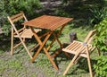 Empty chairs and table table in orchard. Set of folding wooden garden furniture Royalty Free Stock Photo