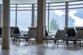 Empty chaise lounge chairs arranged in lobby with view of snowy mountains Royalty Free Stock Photo