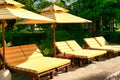 Empty chaise lounges with yellow-white striped mattresses that stand under a sun umbrella with the same pattern. Sanya, Hainan.