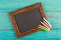 empty chalkboard with copyspace and colorful crayons on wooden table Royalty Free Stock Photo