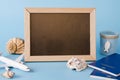 Empty chalkboard with decorative airplane, passports and seashells . Summer travel concept