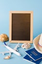Empty chalkboard with decorative airplane, passports and seashells . Summer travel concept