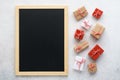 Empty chalkboard and gift boxes on light gray background