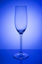 Empty champagne glass on a mirror with spot in blue background Royalty Free Stock Photo