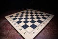 Empty chessboard on wooden table. Dark background