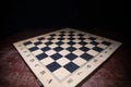 Empty chessboard on wooden table. Dark background