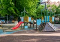 An empty children`s playground in Bucharest, Romania. Children swings and slides in a park with trees Royalty Free Stock Photo