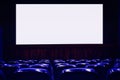 Empty cinema auditorium with empty white screen. Empty rows of theater or movie seats. Blue toned