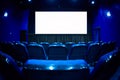 Empty cinema auditorium with empty white screen. Empty rows of theater or movie seats. Blue toned