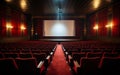 Empty cinema theater with red seats curtains and a blank white screen ready for the audience to enjoy a movie Royalty Free Stock Photo