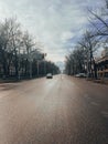 Empty city street with snow-covered trees, distant mountains, and blue sky