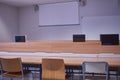 Empty classroom, with chairs, tables, with computers and projector screen Royalty Free Stock Photo