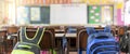 Empty classroom in elementary school with whiteboard and teacher`s desk, school bag hanging Royalty Free Stock Photo