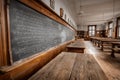Empty classroom with equations written on a large chalkboard and wooden tables Royalty Free Stock Photo