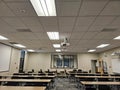 Empty classroom interior, with rows of desks and a projector suspended from the ceiling Royalty Free Stock Photo