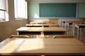 Empty classroom with sunlight streaming through windows and a green chalkboard Royalty Free Stock Photo