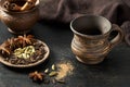 Empty clay cup with natural aroma spices blend, cardamon, anise, cinnamon, in rustic ceramic on dark table