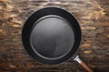 empty clean cast iron skillet on a wooden background.