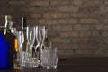 Bottles of whiskey, wine and other alcoholic drinks, different glasses for drinks on the table against old brick wall.Evening at t Royalty Free Stock Photo