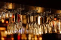 Empty clean upside-down crystal wine glasses hanging from the bar in luxury restaurant. Selective focus blurred Royalty Free Stock Photo