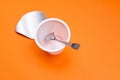 empty clean yogurt cup with spoon on an orange background Royalty Free Stock Photo