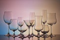 Empty clear glassware. Set of glasses for different alcoholic drinks and cocktails on multicolor gradient background