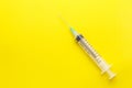 Empty clear syringe with needle on yellow background